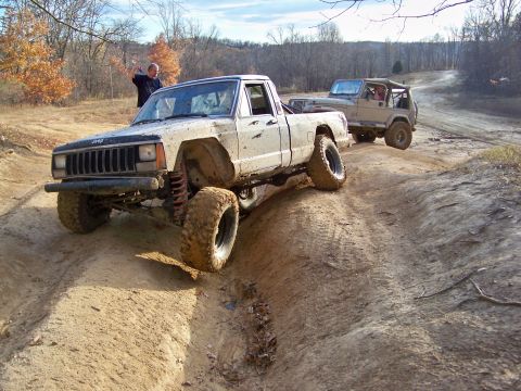 1987 Ford F-250 - Two off-road vehicles navigate a muddy trail during an autumn day.