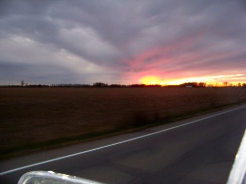 1987 Ford F-250 - A colorful sunset paints the sky over a rural landscape with a road stretching into the distance.