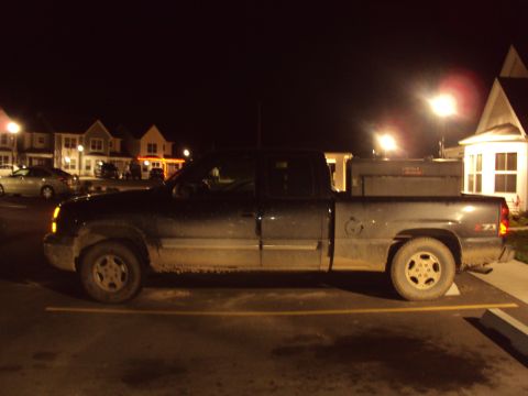 2003 Chevrolet Silverado 1500 - A 2003 Chevrolet Silverado 1500 pickup truck is parked at night, showing its side profile and a toolbox in the bed.