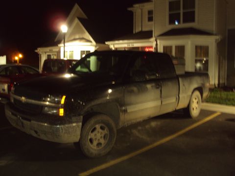 2003 Chevrolet Silverado 1500 - A black 2003 Chevrolet Silverado 1500 pickup truck is parked at night in front of a building.