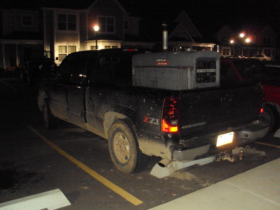 Black 2003 Chevrolet Silverado 1500 pickup truck parked at night with a Lincoln welding machine in the bed