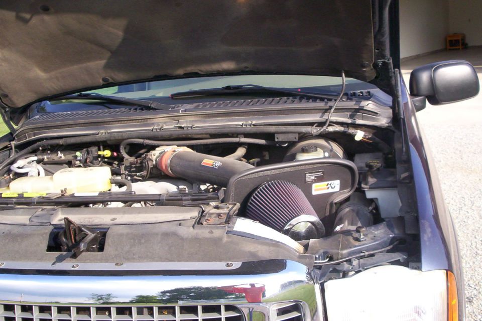 Engine bay of a dark blue Ford truck showing a K&N cold air intake with open cone filter