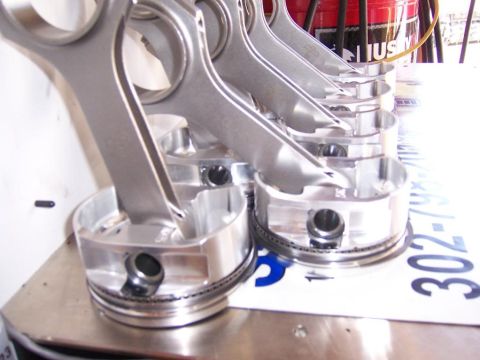 2006 Chevrolet Corvette - Engine pistons and connecting rods are lined up on a surface, with a license plate visible underneath.