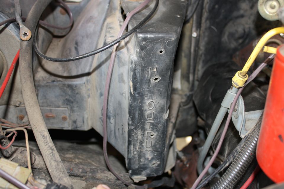 Engine bay with black plastic housing showing stamped text 'H4' and 'OUTLET'