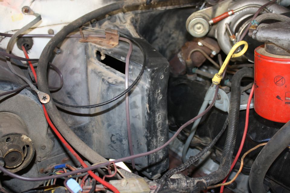 Engine bay detail showing a red oil filter, yellow dipstick, turbocharger components, and wiring harnesses