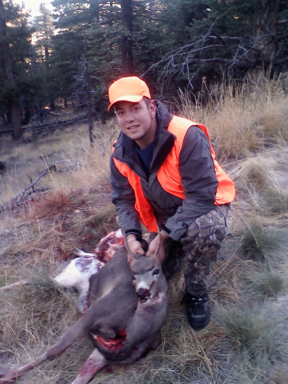 Hunter with harvested deer in wooded area