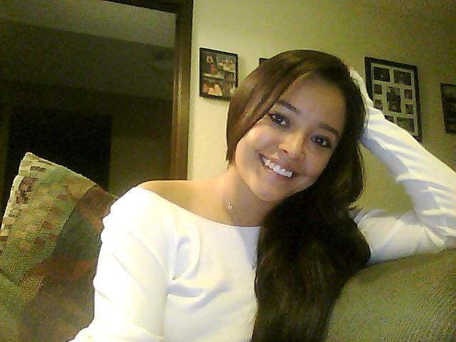 Woman smiling, resting her arm on a couch