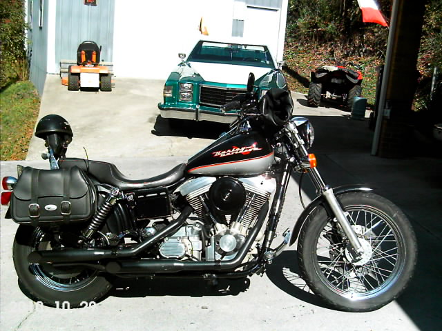 Black Harley-Davidson motorcycle parked in driveway with truck and ATV behind