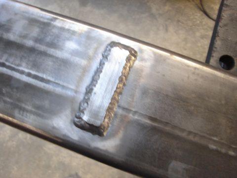 1989 Ford Bronco - Close-up view of a metal frame a freshly welded rectangular patch.