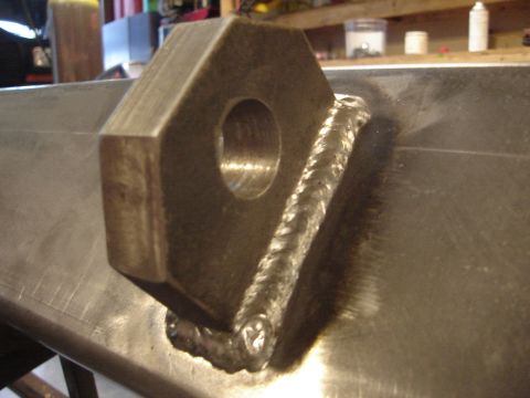 1989 Ford Bronco - A metal bracket with a hole is securely welded to a flat metal plate, showing industrial fabrication.