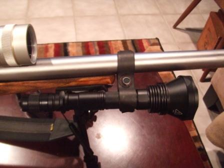 1996 Ford Bronco - A close-up view of a rifle scope and tactical flashlight mounted on a firearm.