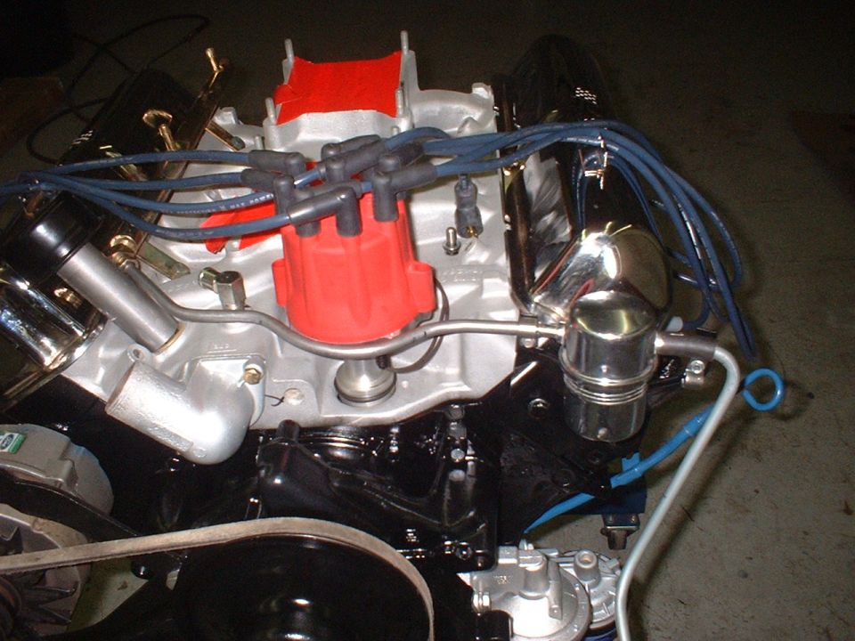 Close-up of a V8 engine with a red distributor cap and blue spark plug wires