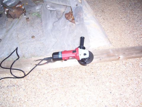 1992 Ford Bronco - An angle grinder sits on a wooden plank, with a plastic sheet and debris in the background.