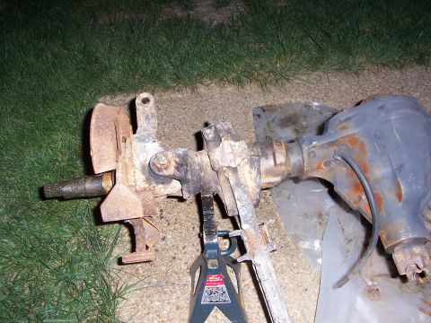 1992 Ford Bronco - A rusty front axle assembly is supported by jack stands on the ground.