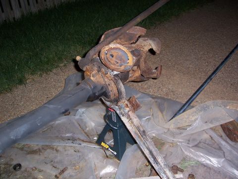 1992 Ford Bronco - Rusted front axle assembly supported by jack stands on a driveway.