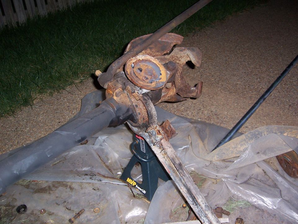 rusted front axle assembly on jack stands