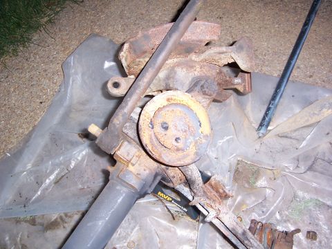 1992 Ford Bronco - A heavily rusted steering gear assembly is shown, with a yellow circular component and a metal rod. The part is placed on a sheet of plasti…