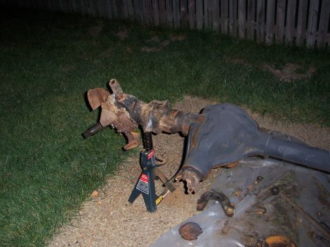 1992 Ford Bronco - Front axle assembly, likely from a truck or SUV, resting on jack stands in a grassy yard.
