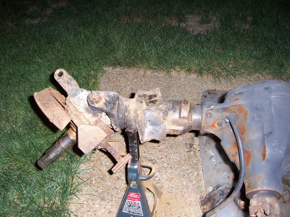 Front axle assembly with brake components and differential housing, resting on jack stands