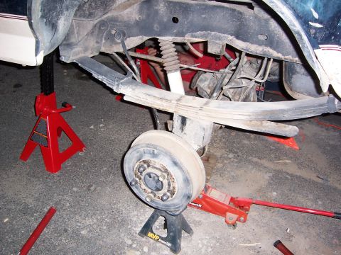 1992 Ford Bronco - The rear suspension of a vehicle is being worked on, supported by jack stands and a hydraulic jack.