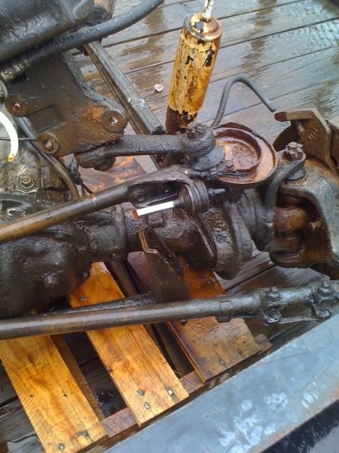 1992 Ford Bronco - Close-up of a heavily corroded front axle assembly, likely from an older truck or SUV, on wooden planks.