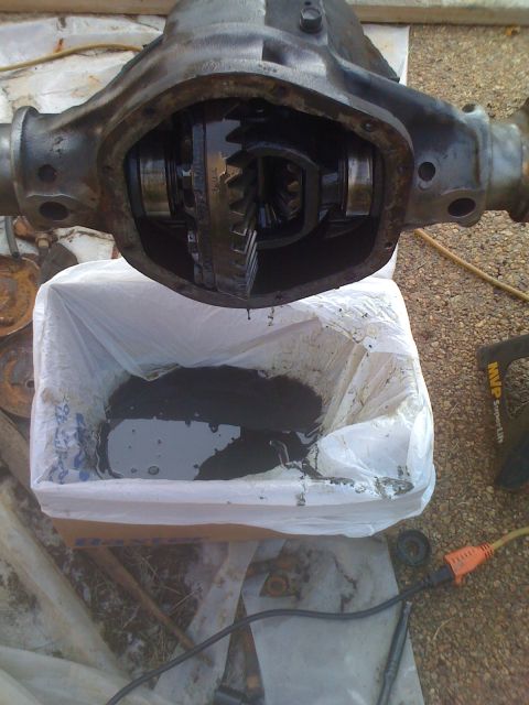 1992 Ford Bronco - Differential housing with gears visible, draining into a plastic bag on the ground.