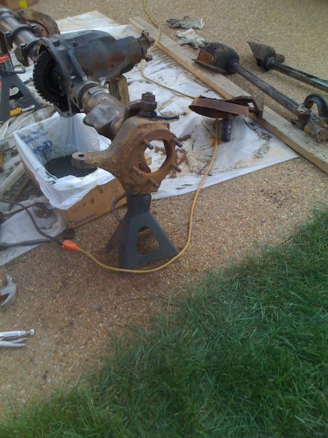 1992 Ford Bronco - Front axle assembly and driveshafts are laid out on a tarp, supported by jack stands.