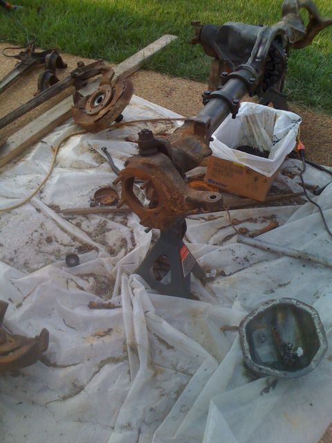 1992 Ford Bronco - Vehicle axles and suspension components laid out on a tarp for work.