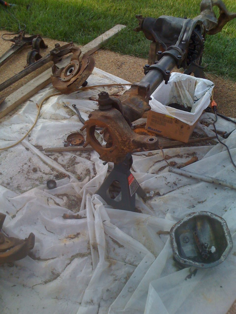 Disassembled vehicle axles and suspension parts on a tarp