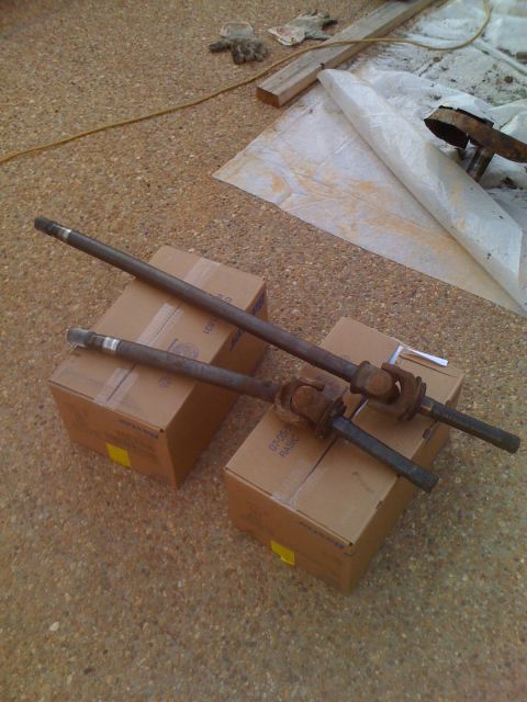 1992 Ford Bronco - Two drive shafts are placed on top of cardboard boxes, with some tools and wood in the background.