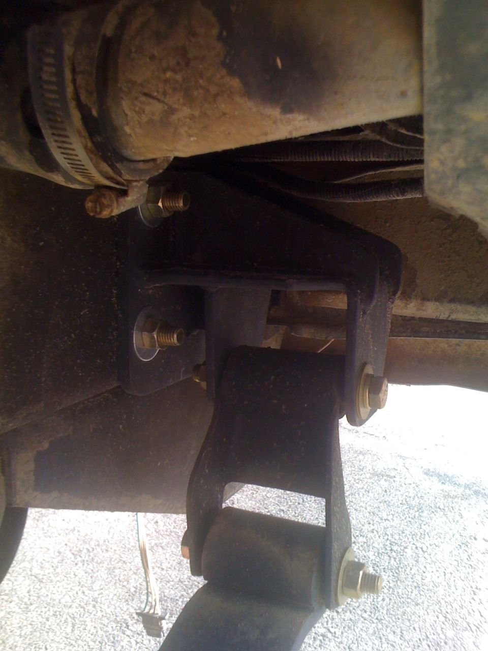 Close-up of a vehicle's rear suspension linkage with bolts and a hose clamp