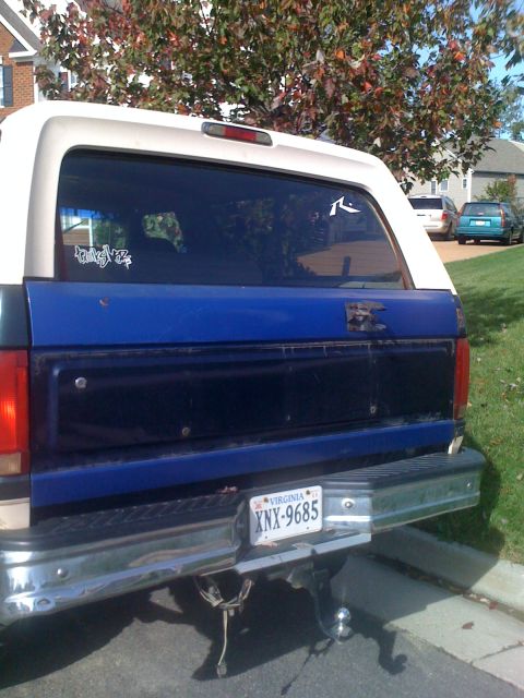 1992 Ford Bronco - Rear view of a 1992 Ford Bronco with a blue tailgate and white camper shell.