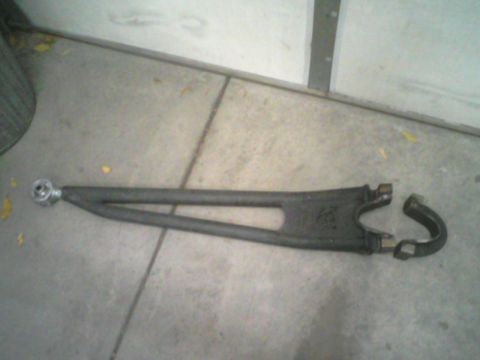 1993 Ford Bronco - A single automotive suspension control arm is shown on a concrete surface.