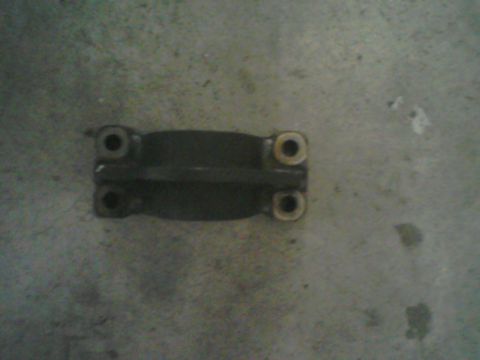 1993 Ford Bronco - A dark metal automotive part with four visible bolt holes is shown against a concrete background.