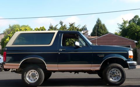 1995 Ford Bronco - Side view of a classic Ford Bronco, showing its two-tone paint and elevated stance.