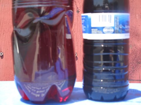 1995 Ford Bronco - Two bottles containing dark colored fluids are shown against a red wooden surface.