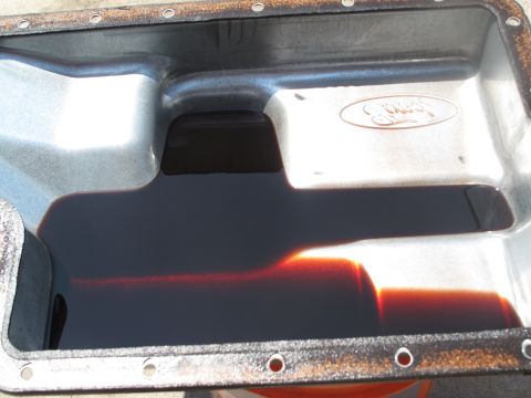 1995 Ford Bronco - Transmission pan showing dark fluid, with a Ford logo embossed on the side.