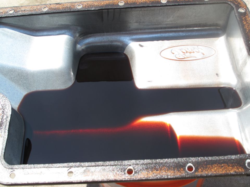 Ford transmission pan with dark fluid and visible Ford logo