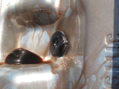 1995 Ford Bronco - Close-up of a transmission pan interior showing dark fluid and a black plug, likely related to a transmission upgrade.