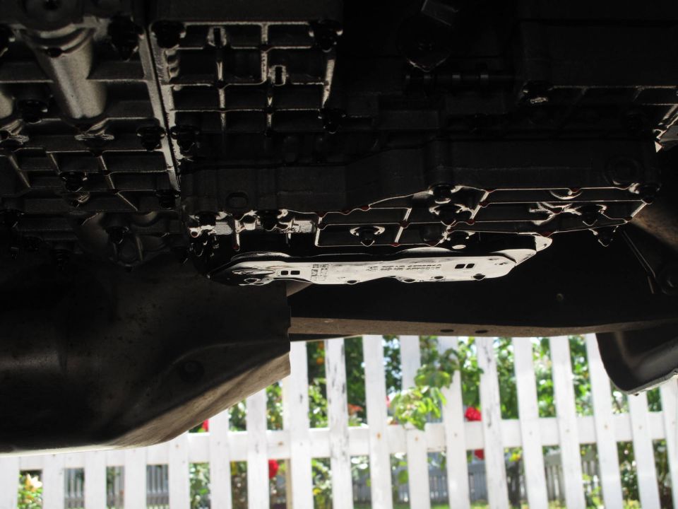 Underside view of a vehicle's transmission pan with visible part numbers