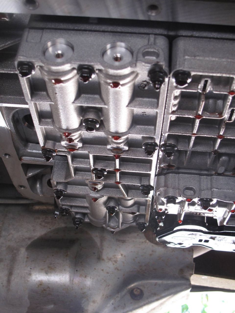 close-up of a transmission valve body with red fluid visible