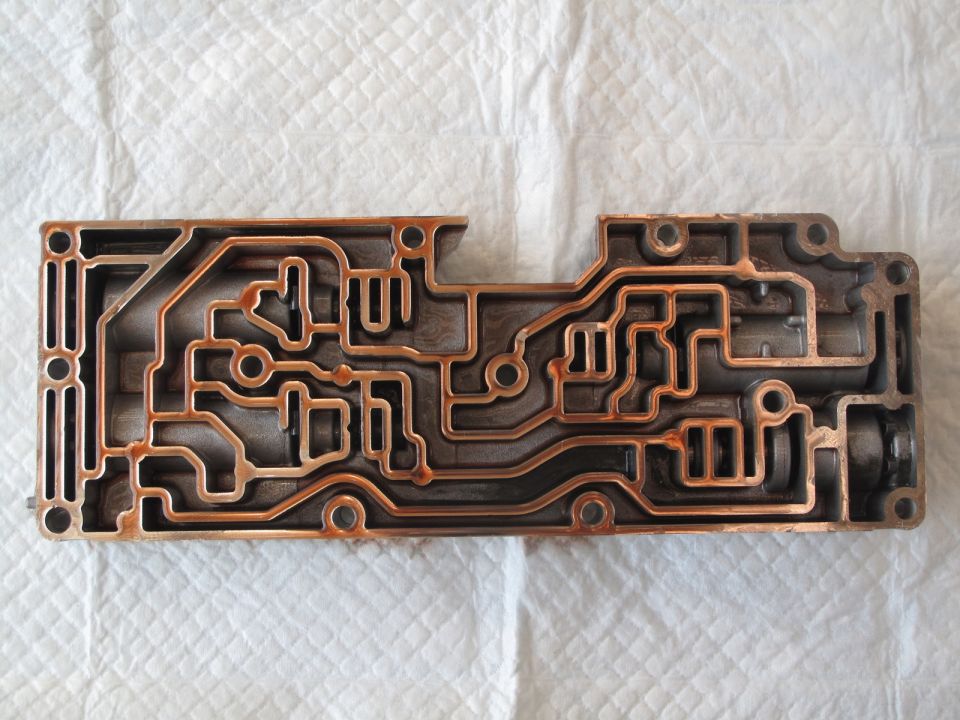 Metal valve body with complex internal channels, showing some rust
