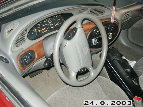 1998 Mercury Sable - The interior of a 1998 Mercury Sable features wood trim accents and a gray dashboard with a prominent steering wheel.