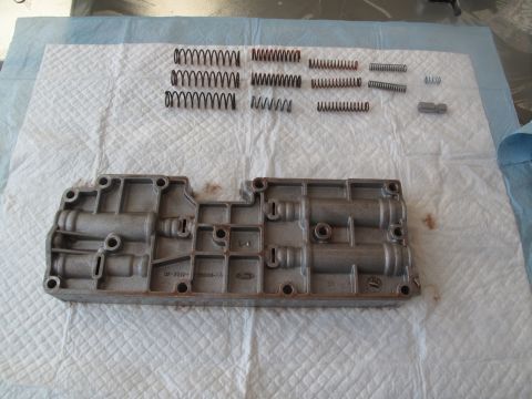 1995 Ford Bronco - Transmission valve body and assorted springs are disassembled on a white surface.