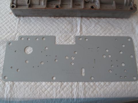 1995 Ford Bronco - Transmission valve body and gasket, possibly from a Ford vehicle, shown on a white textured surface.