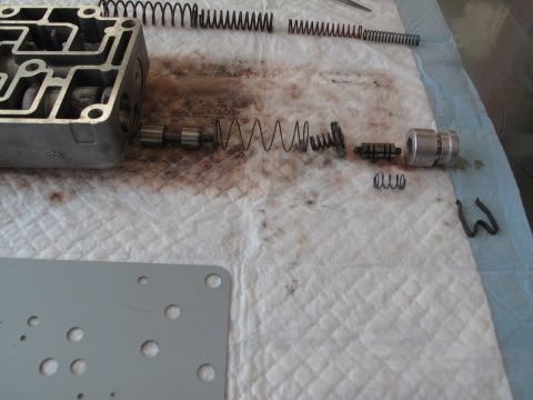 1995 Ford Bronco - Disassembled transmission valve body with various springs and internal parts shown on a white surface.
