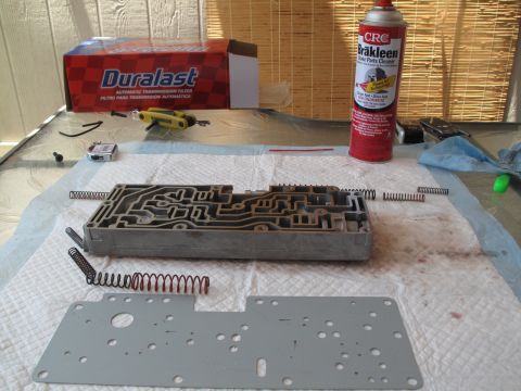 1995 Ford Bronco - A transmission valve body and related parts are laid out for service, with cleaning supplies nearby.