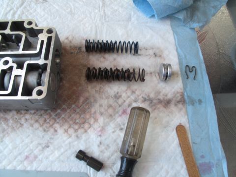 1995 Ford Bronco - Disassembled transmission valve body components, including springs and a plunger, laid out on a cloth with a screwdriver.