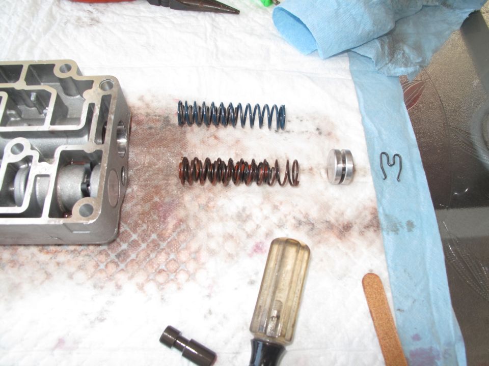 Transmission valve body disassembled with springs and tools on a workbench