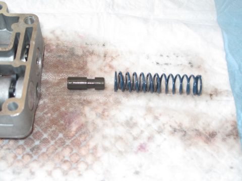 1995 Ford Bronco - A disassembled transmission component, including a spring and pin, is laid out on a white surface.